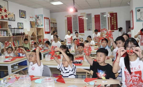 实践团成员与孩子们共同创作剪纸作品。重庆师范大学美术学院供图